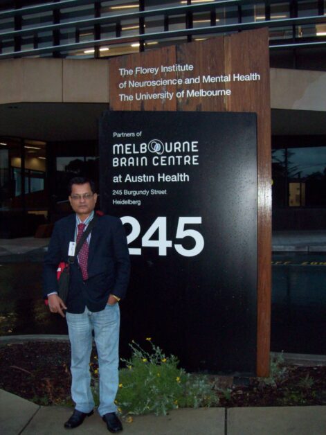 Dr. Tarit Kanti Ghosh standing in front of the Melbourne Brain Centre sign at Austin Health.