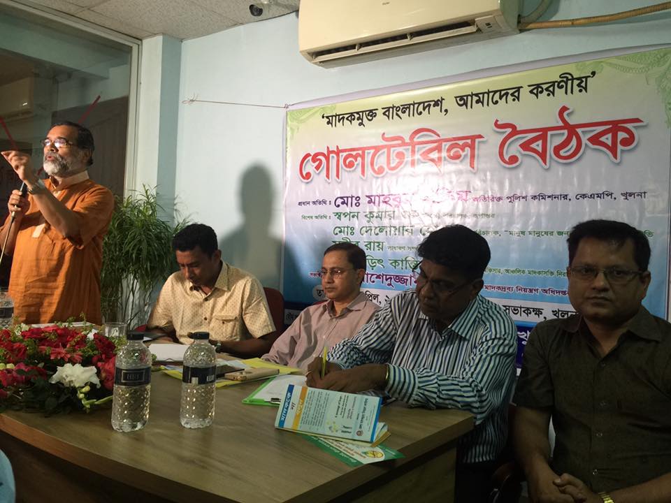 Dr. Tarit Kanti Ghosh participating in a roundtable discussion with other panel members, with a banner in the background.
