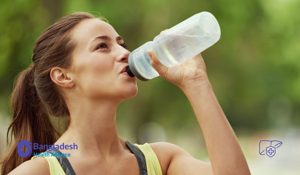 Hydrate for Optimal Liver Function: A woman drinking water from a bottle while exercising outdoors. 