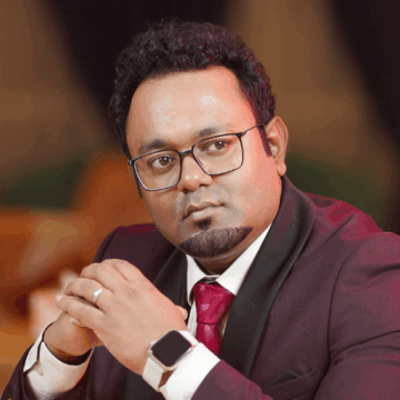 Formal close-up headshot of Dr. Partha S. Barai in a maroon suit, renowned ophthalmologist and eye surgeon based in Bogura.