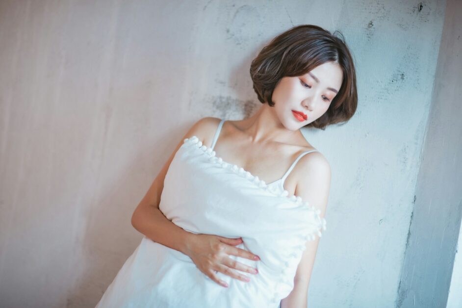 A woman in a white dress leaning against a wall
