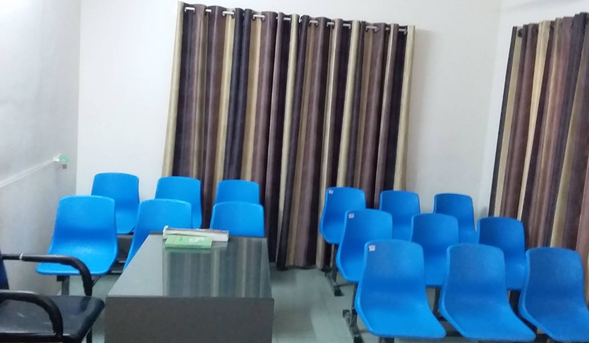 The clean and simple waiting area of the Homeo Care clinic with rows of blue chairs.