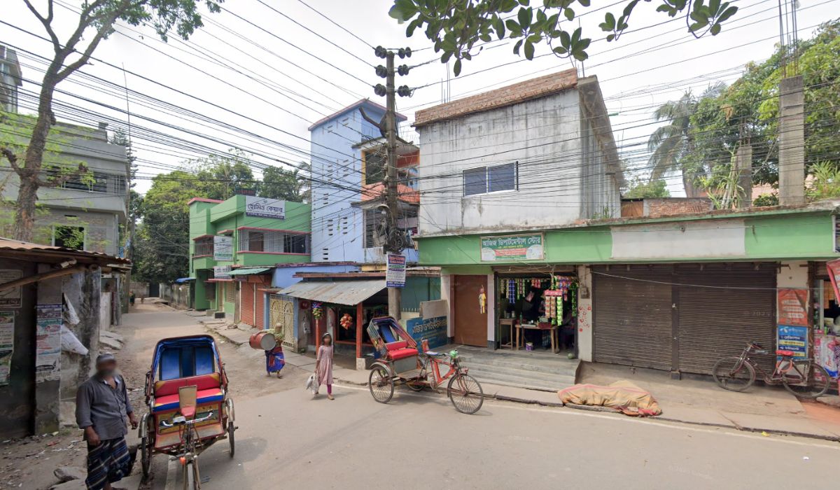 A general street view of the area in Jessore where the Homeo Care clinic is located, with other shops and rickshaws.