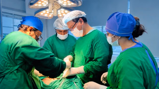 Surgeons providing oral cancer treatment under modern operating-room lights